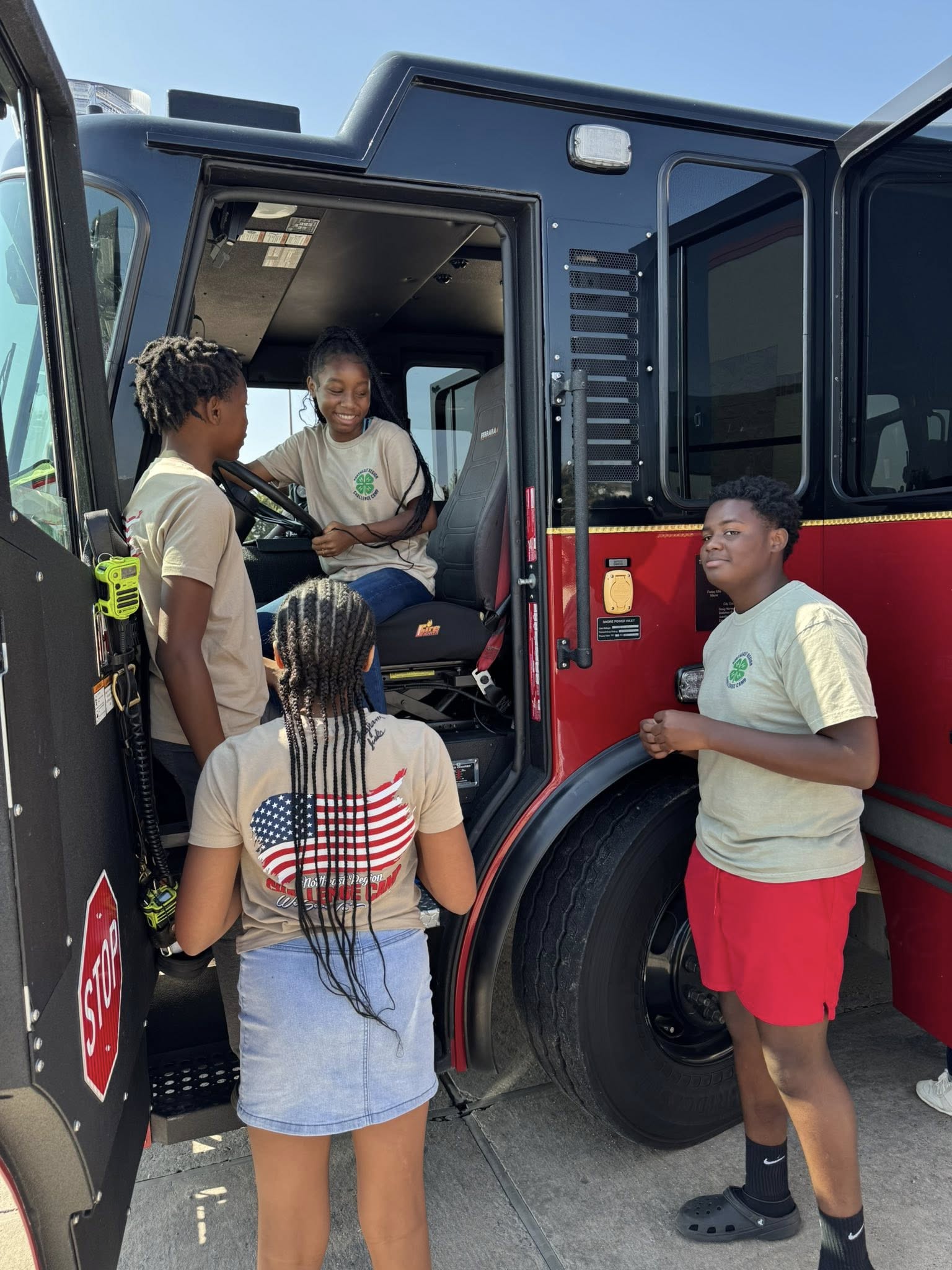 Four kids by a fire truck.